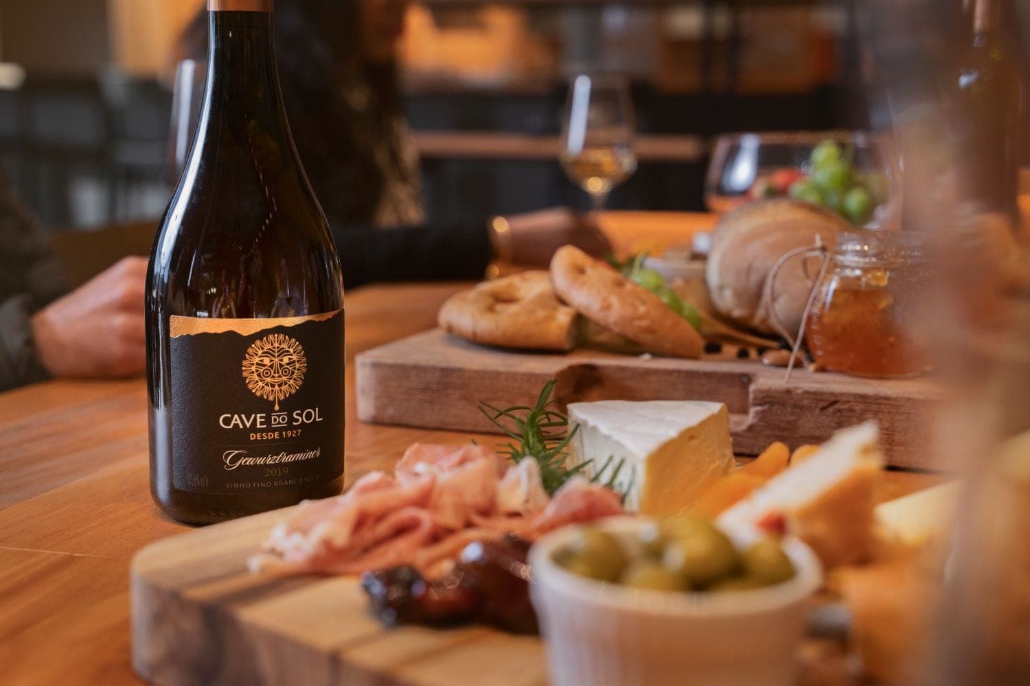 Vinho Cave do Sol à mesa com queijos, pães e acompanhamentos na vinheria