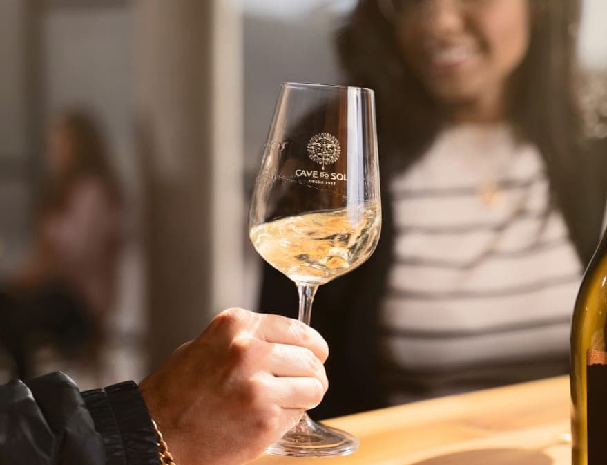 Uma taça de vinho branco à mesa da Cave do Sol
